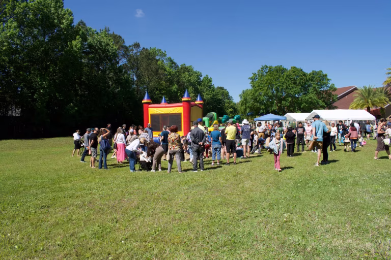 a group of people gathered around a bounce house at a festival